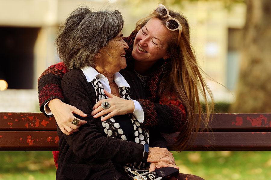 Moeder en dochter samen knuffelend op een bankje