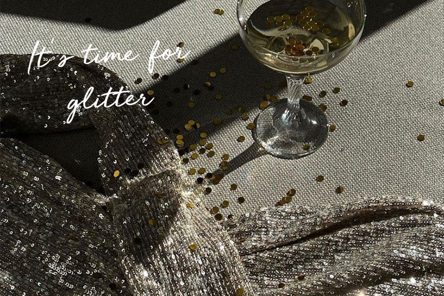 Glitterstof met losse confetti en glas champagne