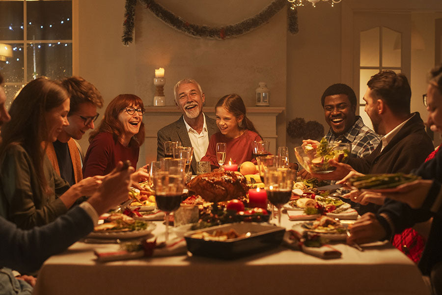Hele familie netjes gekleed aan tafel tijdens het kerstdiner gezellig met versierde tafel en kerstdecoratie